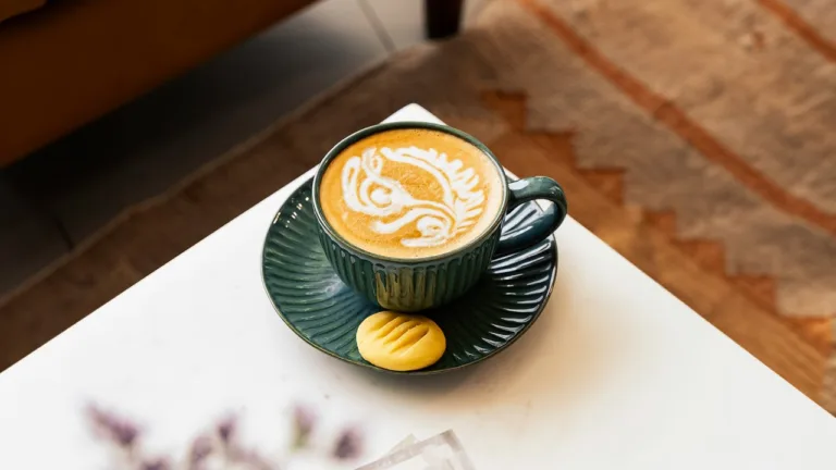 Latte art in a green cup on a white table – minimalist coffee photography by My Pinch of Wow, Dubai
