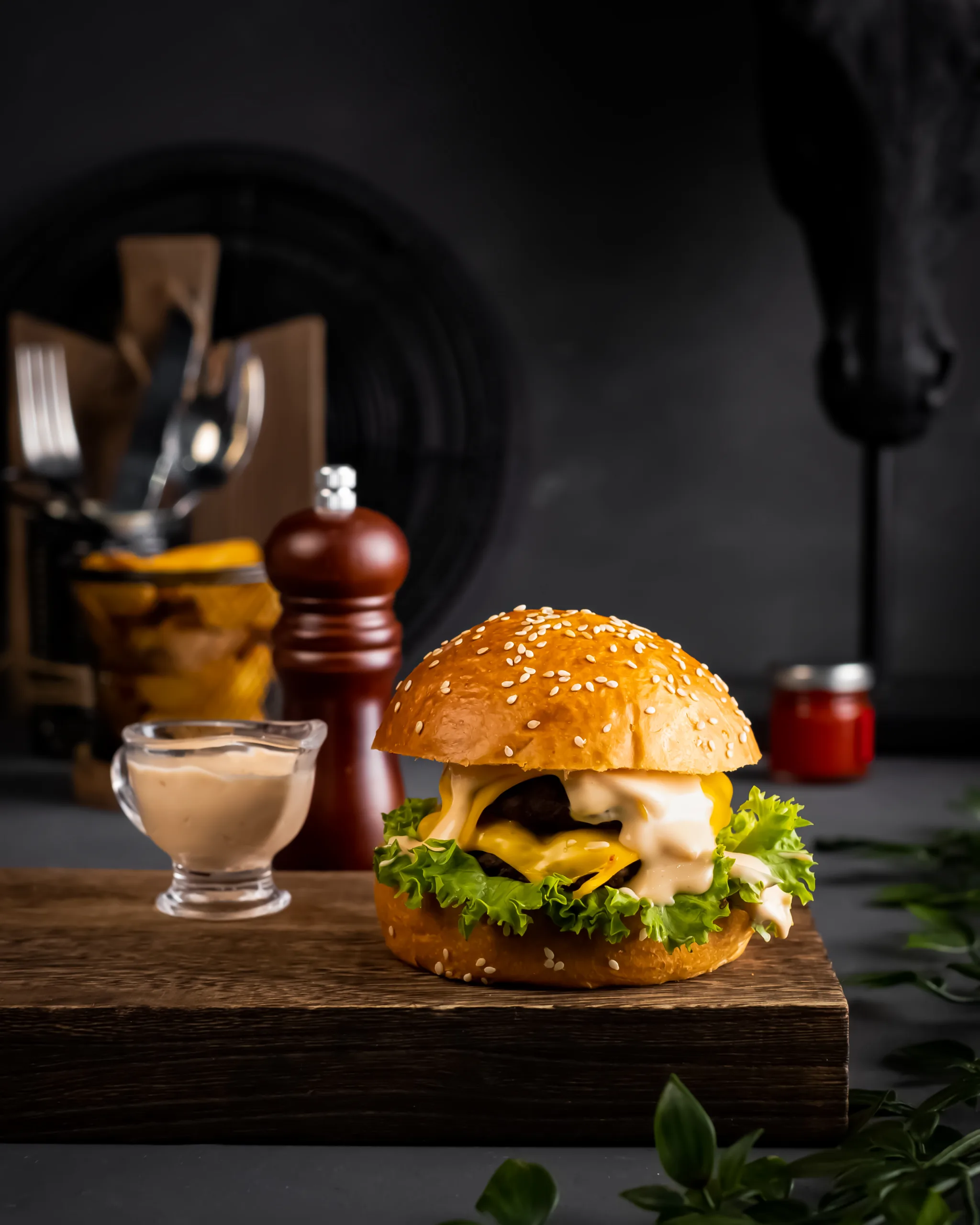 Cheeseburger with melted cheese and sauce on a dark background with props – burger photography, Dubai