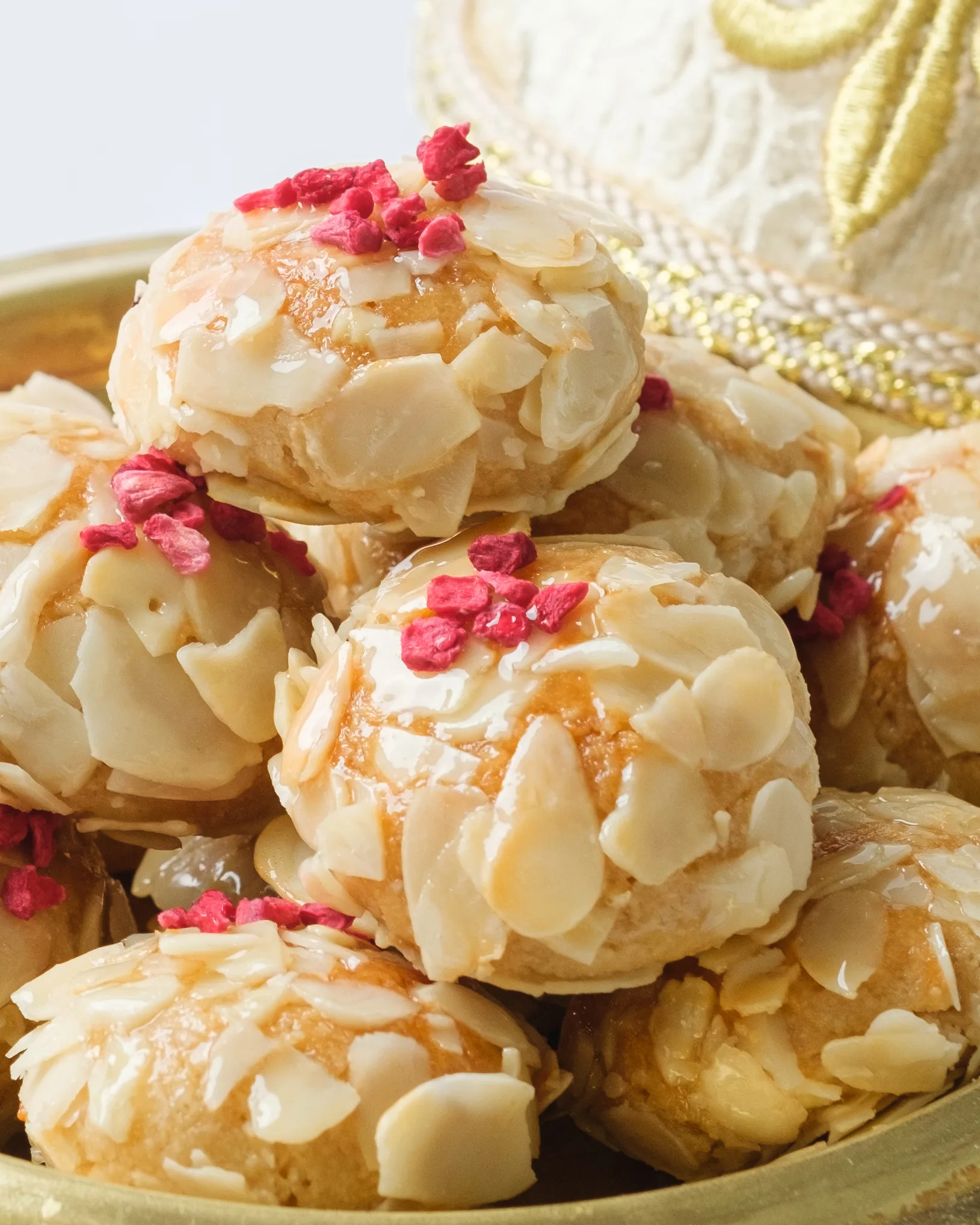 Almond-flake choux pastries with freeze-dried raspberries on a gold tray – dessert photography, Dubai