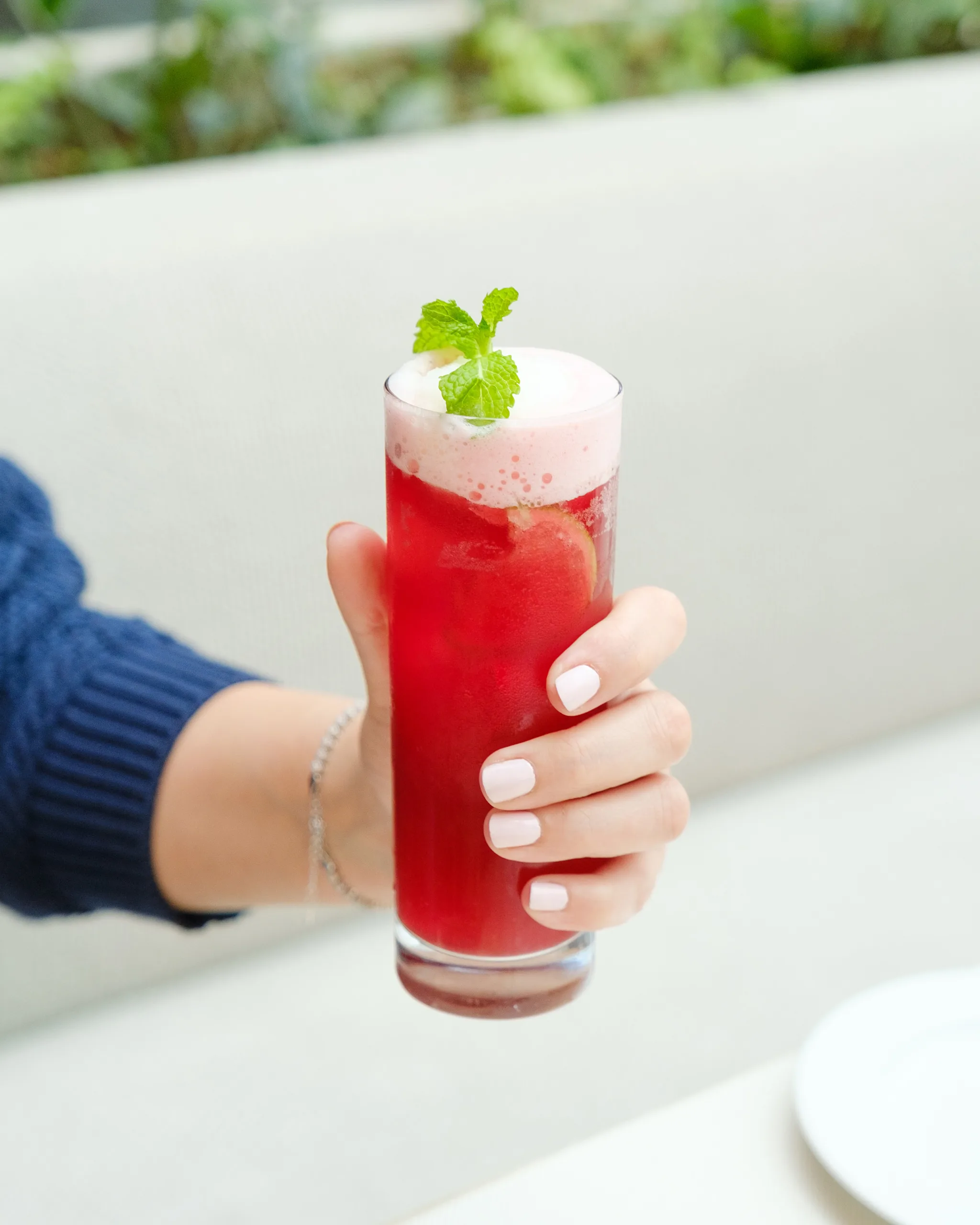 Hand holding a pink fizzy cocktail with mint – bar drink photography, Dubai
