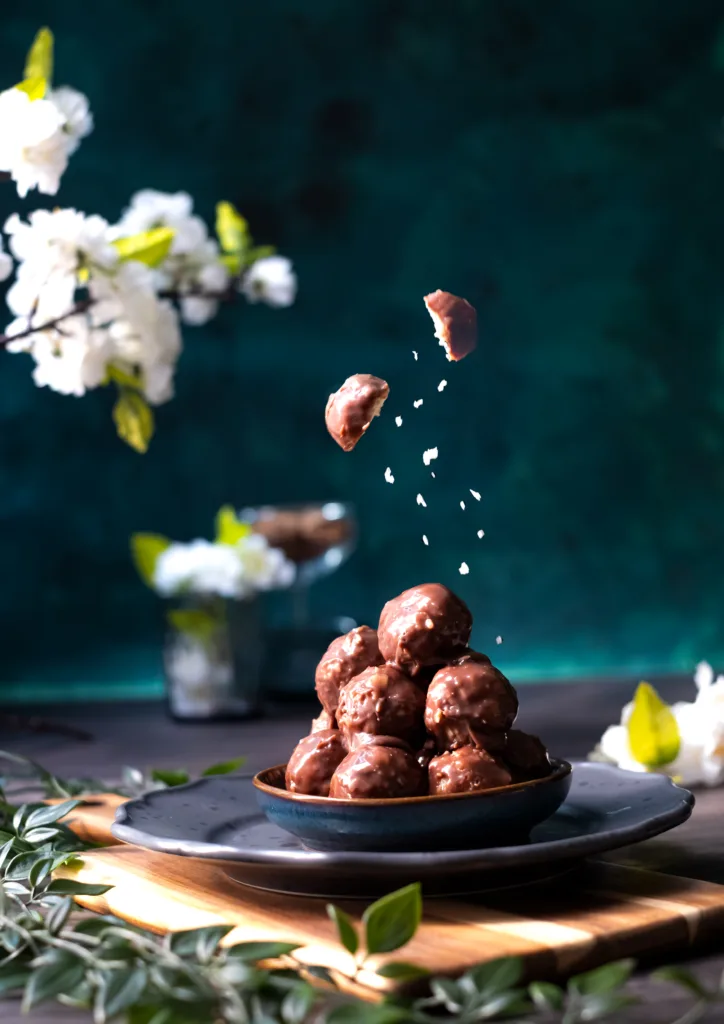 Chocolate truffles falling with cocoa dust onto a dark plate – levitation dessert photography, Dubai
