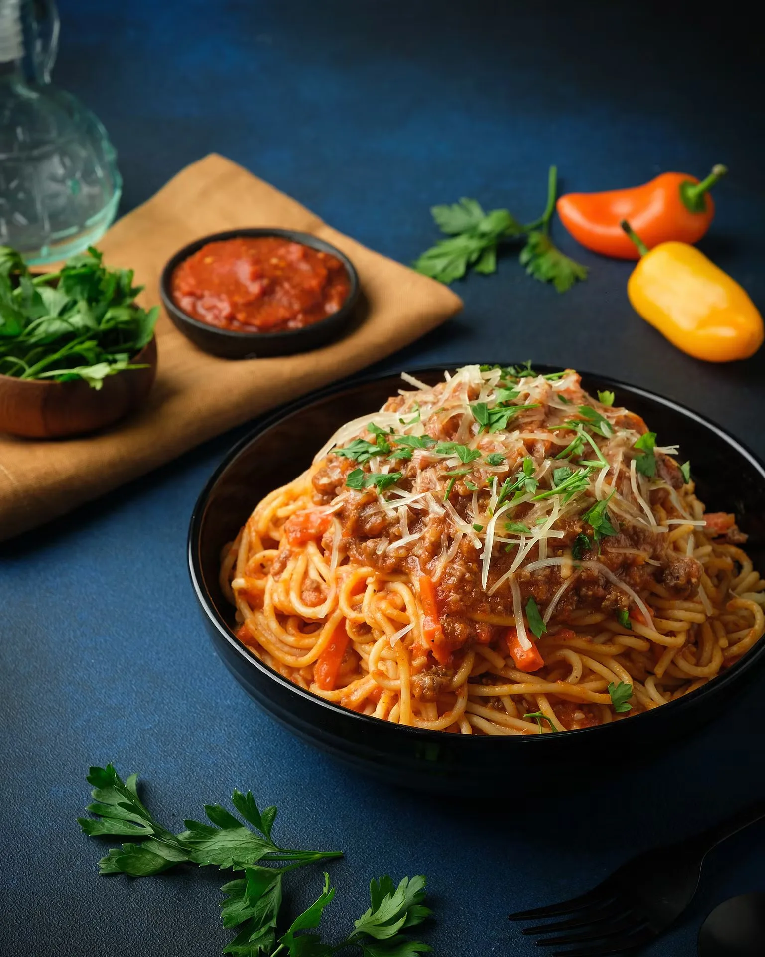Spaghetti bolognese in a black bowl with parmesan and condiments – restaurant menu photography by My Pinch of Wow, Dubai
