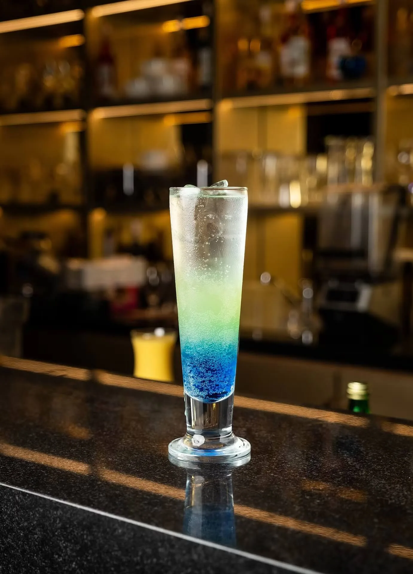 Layered blue cocktail in a tall glass at a bar – beverage photography for restaurants and bars, Dubai