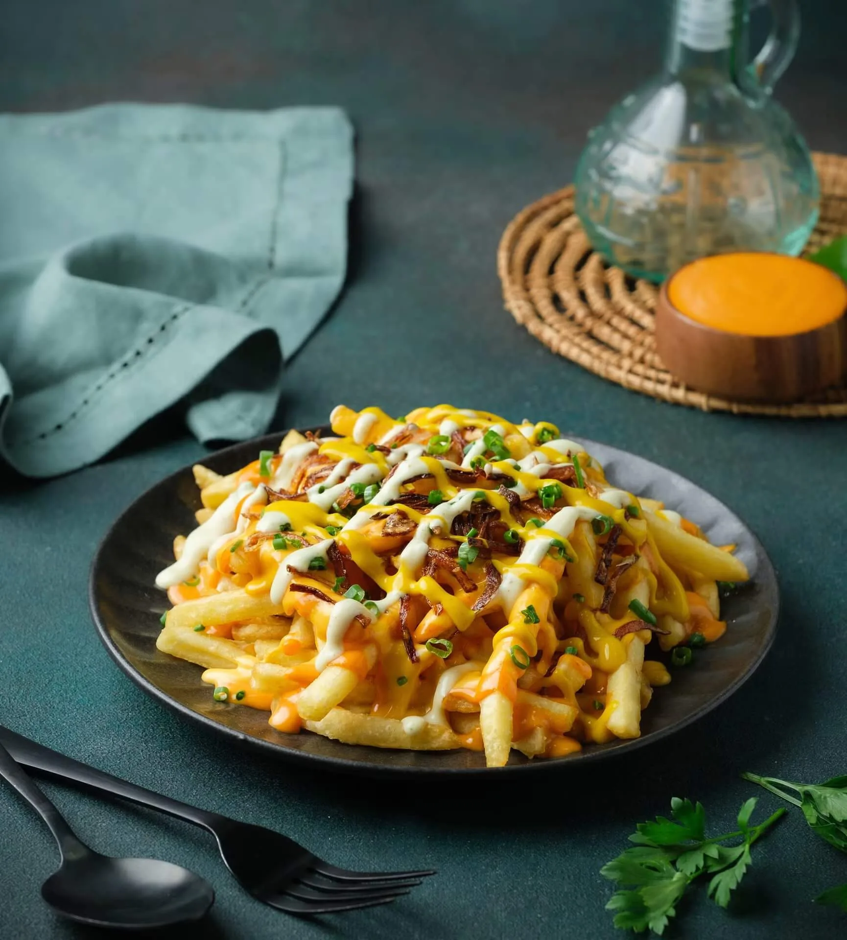 Loaded cheesy fries in a black bowl with dipping sauce – fast-food menu photography, Dubai