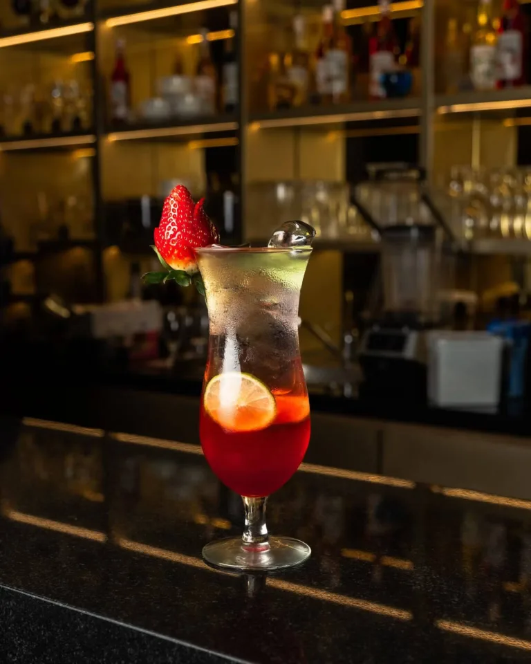 Red berry cocktail with a strawberry garnish at a bar – drink photography, Dubai