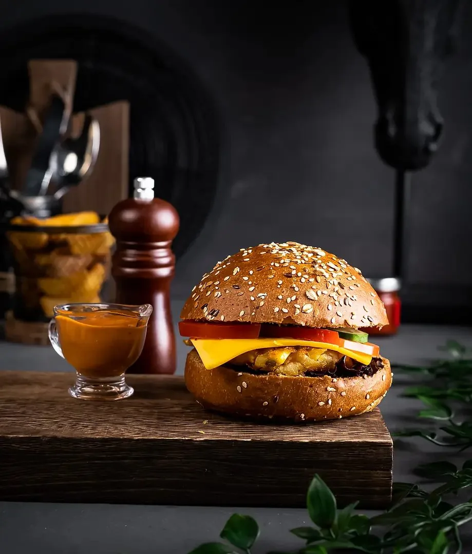Cheeseburger with melted cheese and sauce on a dark background – burger photography, Dubai