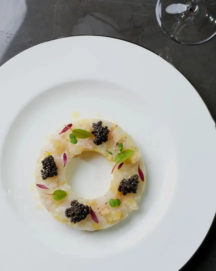 Ring of tartare crowned with black caviar pearls on a white plate – fine-dining food photography, Dubai