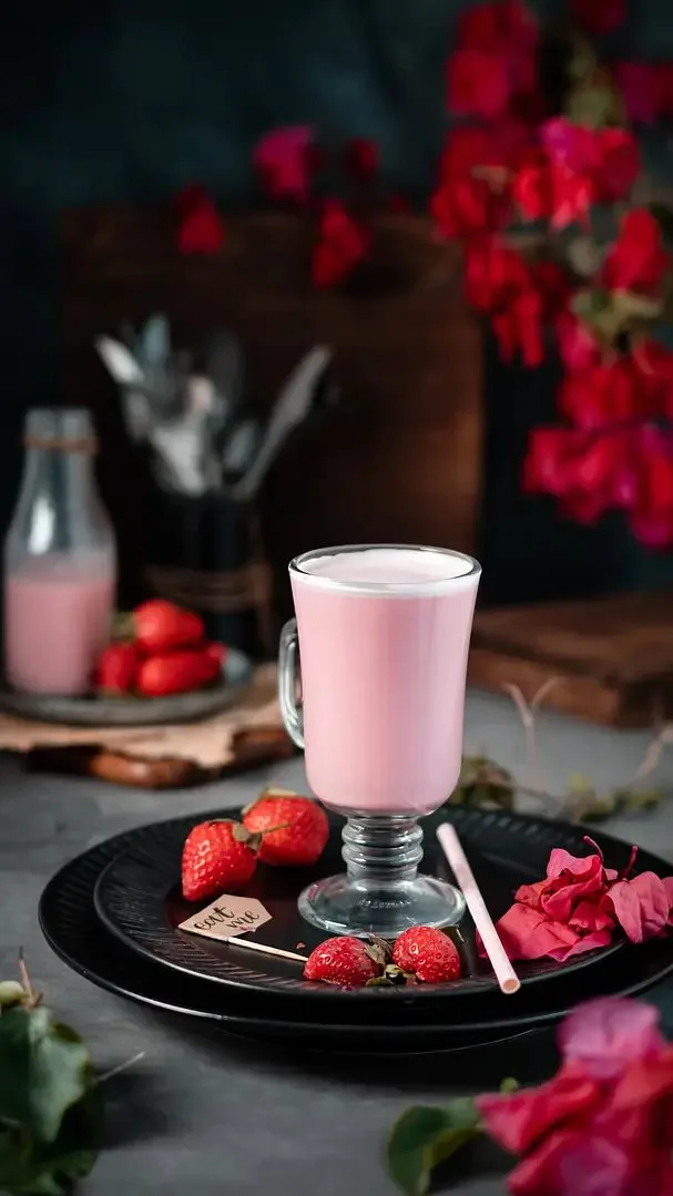 Strawberry milkshake in a glass mug with a bottle of pink milk – café beverage photography, Dubai