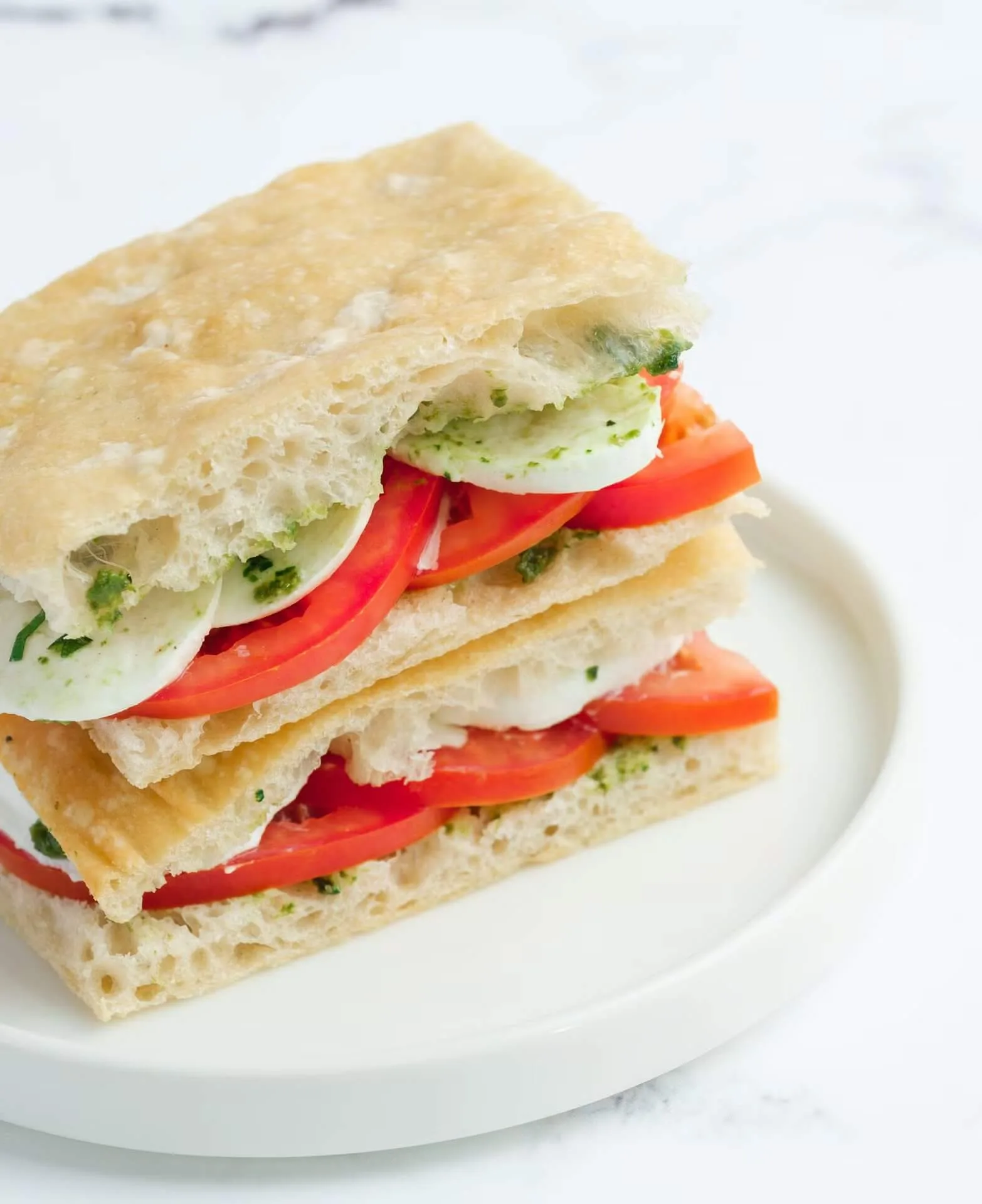 Layered flatbread sandwich with tomato and cucumber on a white plate – café menu photography, Dubai