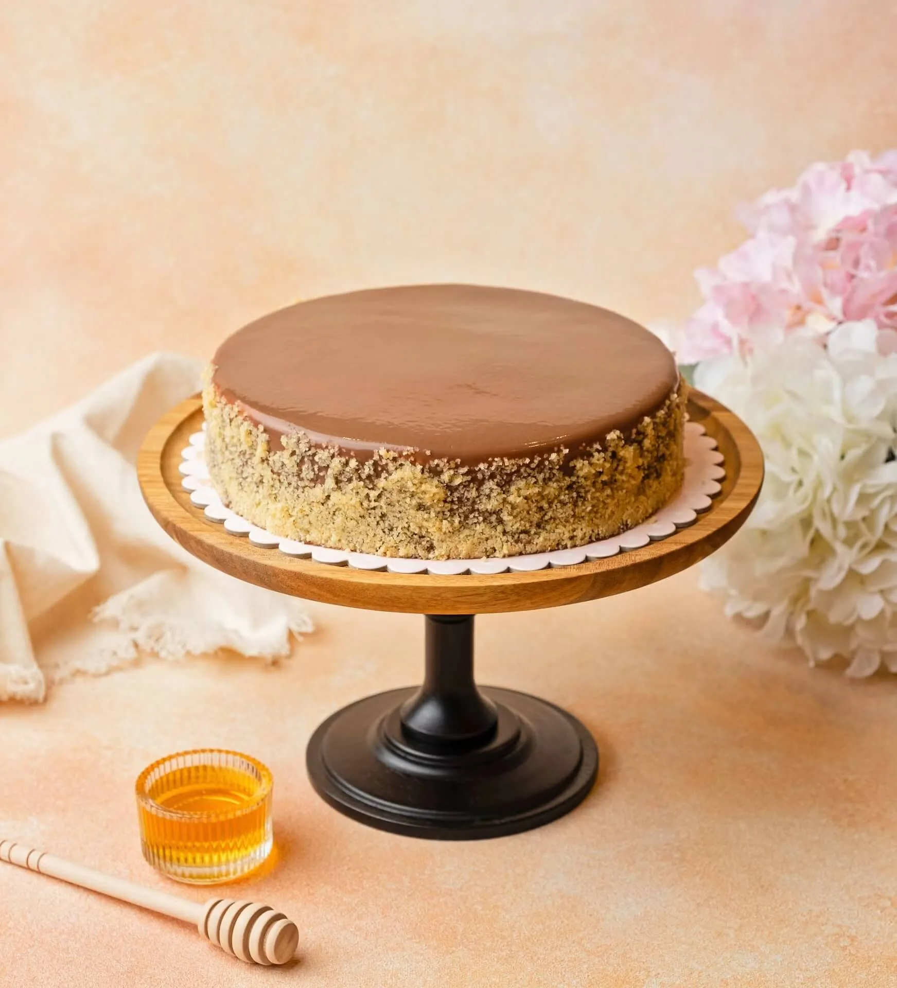 Caramel-glazed round cake on a cake stand with flowers – bakery and cake photography, Dubai